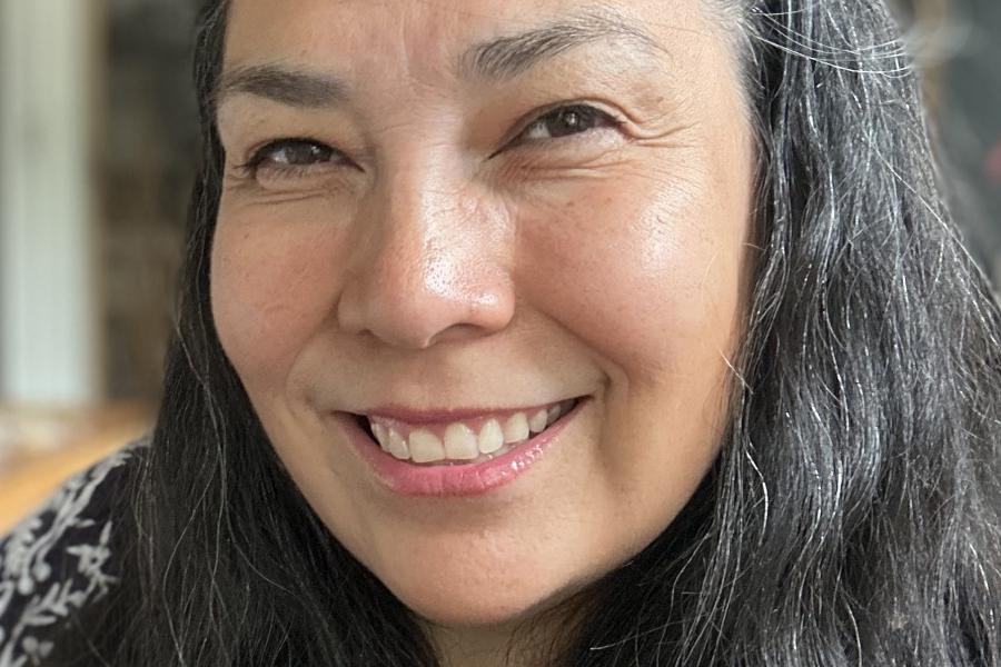 Face of KC Adams, with long black hair, smiles towards the camera