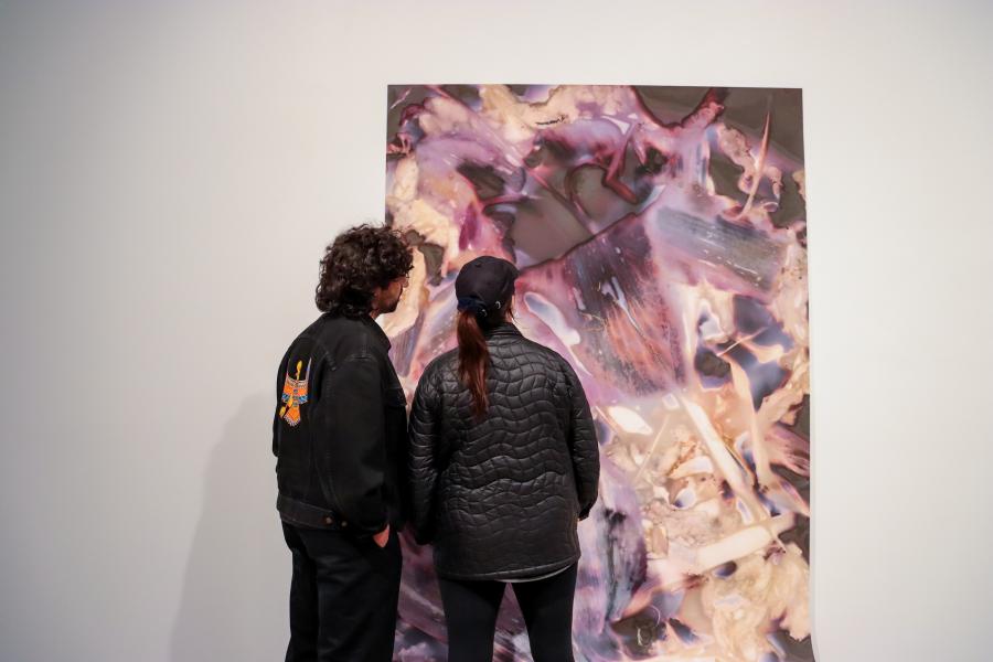 Two visitors observing a large abstract photographic work at the "What If the Sun Didn’t Rise" exhibition.