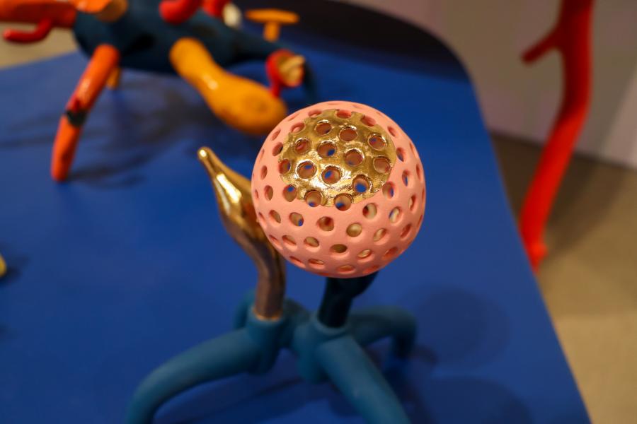 A glossy, deep blue bulb-like ceramic piece with gold accents on its stem, placed on a green surface.