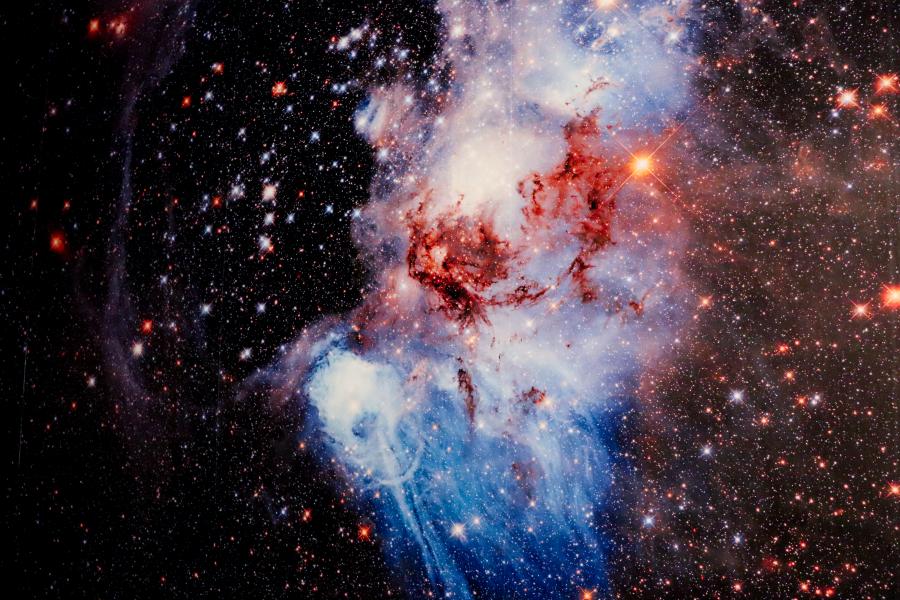 A vivid representation of a cosmic nebula, resembling an astronomical phenomenon with intense reds, blues, and bright stars.