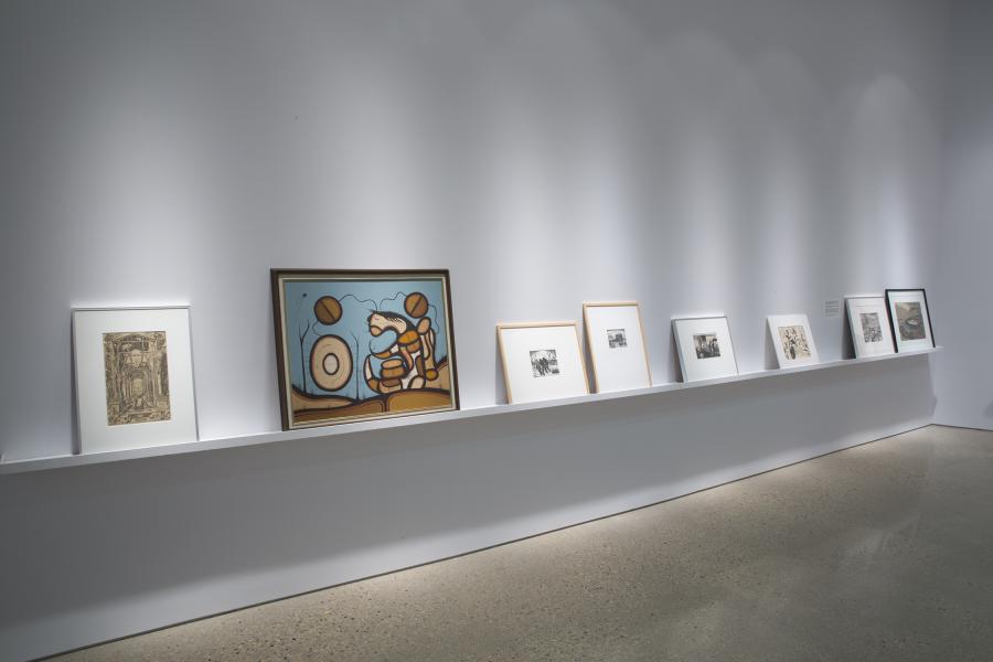 A closer view of framed artworks arranged on a sleek white shelf, including prints and photographs.