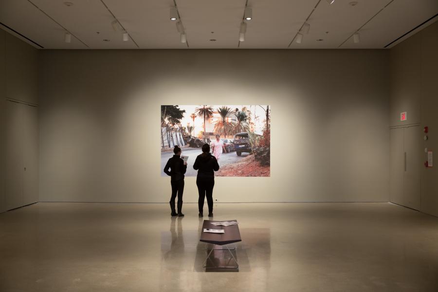 Gallery visitors observing a photograph of a woman walking a dog, part of Lidwien van de Ven's exhibition.