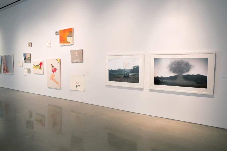A gallery wall featuring various small and medium-sized works, including paintings, drawings, and photographs arranged in a curated display.