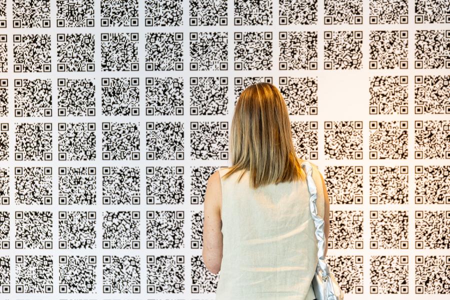 A women stands infront of a wall of QR codes