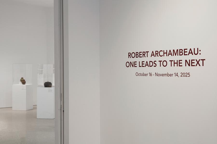 The gallery entrance shows the exhibition title ‘Robert Archambeau: One Leads to the Next’ with ceramic works visible inside.