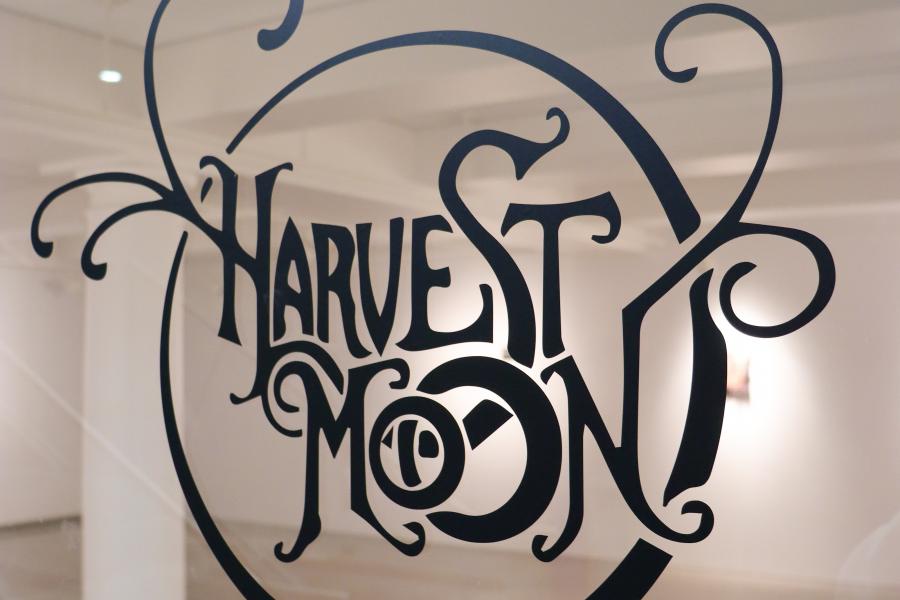 Decorative vinyl text reading “Harvest Moon” applied to a glass gallery wall.
