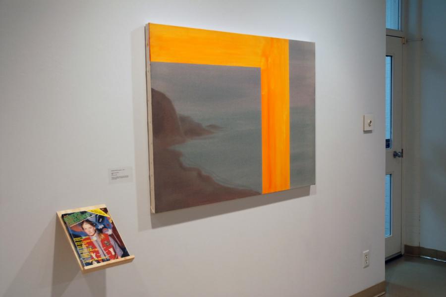 A painting and a magazine on a wall. The painting depicts cloudy seaside cliffs, with a thick bright orange column asymmetrically bisecting the scene and framing the top on the larger left side. To its lower left, a shelf holds a magazine with a cover photo of a woman in a red vest with a kabuki-styled blue face behind her.