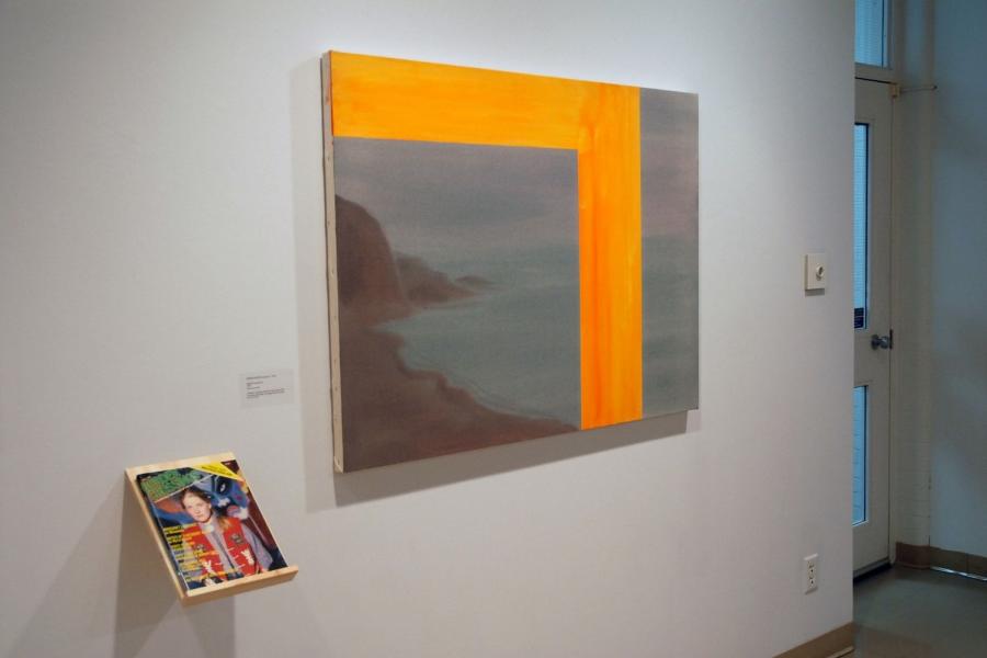 A painting and a magazine on a wall. The painting depicts cloudy seaside cliffs, with a thick bright orange column asymmetrically bisecting the scene and framing the top on the larger left side. To its lower left, a shelf holds a magazine with a cover photo of a woman in a red vest with a kabuki-styled blue face behind her.