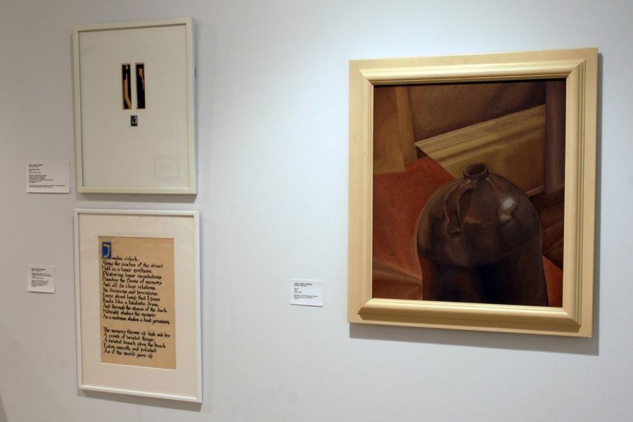 Three artworks on a wall. On the top left are two small black strips with brown shapes on them, and a small black square beneath them with a white letter A on it, all sharing a frame. On the bottom left is an abridged version of the poem Rhapsody on a Windy Night by T S Eliot written in black gothic script on a beige paper, and a stylized first letter T in yellow on blue. On the right is a painting of a black jug seen from above on a red and brown background.