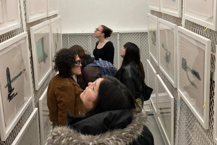 Visitors viewing framed artworks in a narrow gallery space at the School of Art.