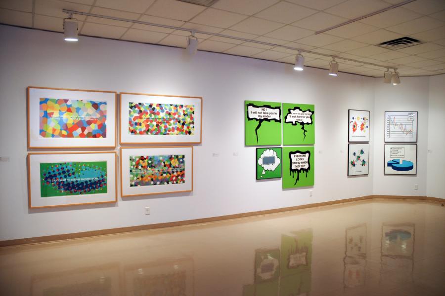 Wide gallery view showing colourful paintings and graphic artworks installed throughout the exhibition space.