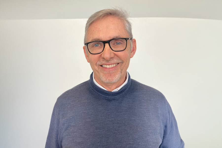 Headshot of faculty member Oliver Botar, smiling, wearing black glasses and a blue sweater over a white collared shirt.