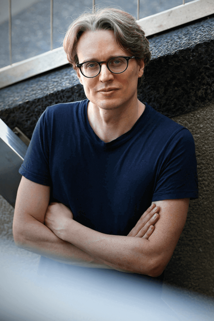Headshot of Dr. Neil McArthur standing against a wall.