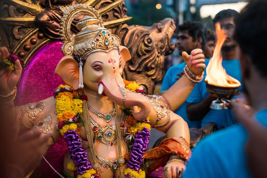 Idol of Hindu deitie Ganesha on display with people in blue T-shirts surrounding it.