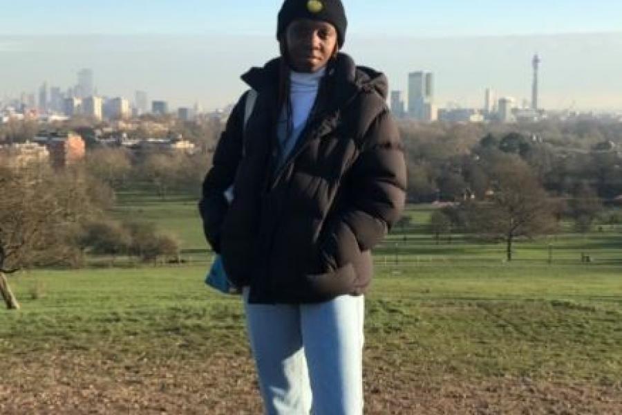 Woman in parka and toque standing in front of a cityscape.