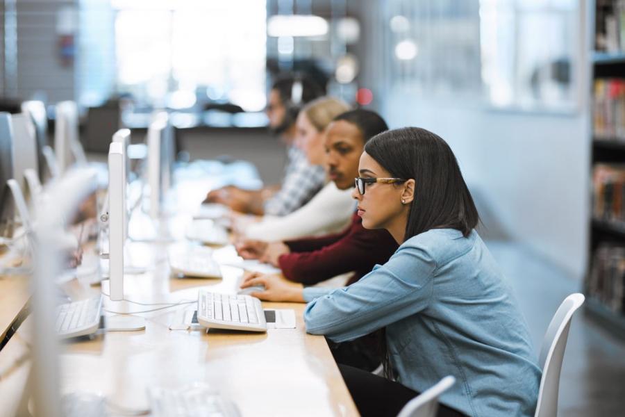 Row of students looking at desktop computers.