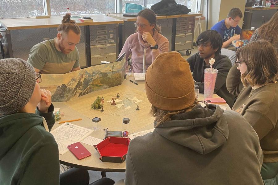 Five people sitting around a table playing the game dungeons and dragons.