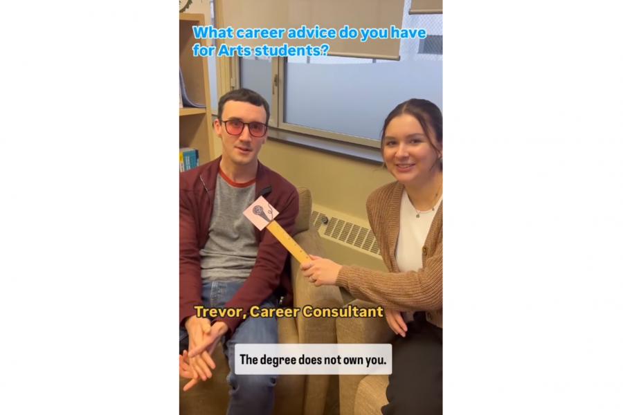 A student interviewing an alumni using a ruler as a fake microphone.