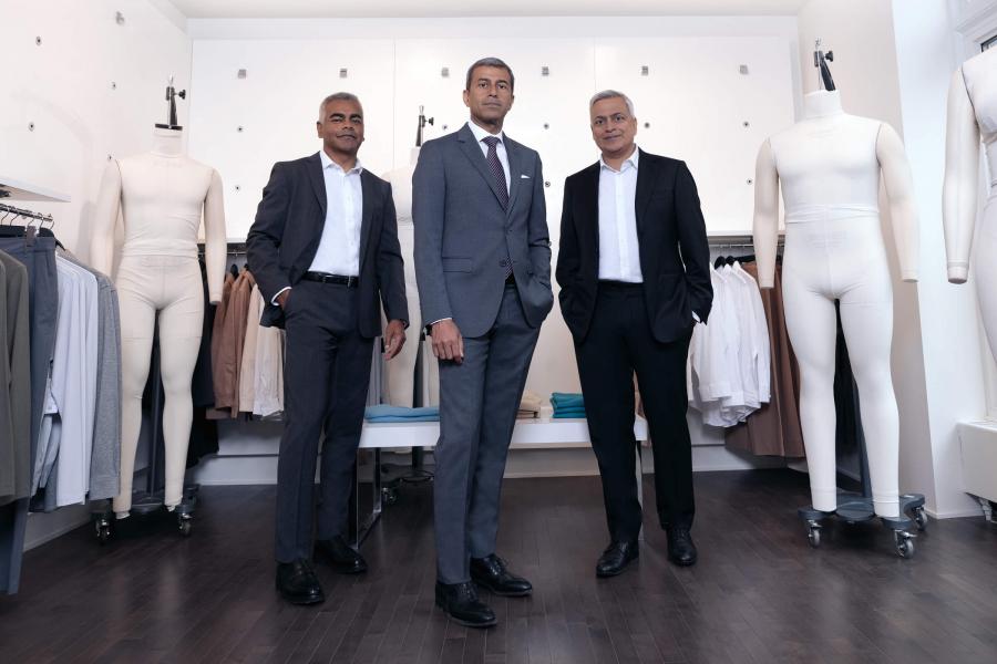 Three men in suits standing in a retail space.