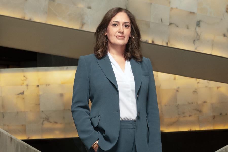 Isha Khan wearing a suit, one hand is in her pocket.