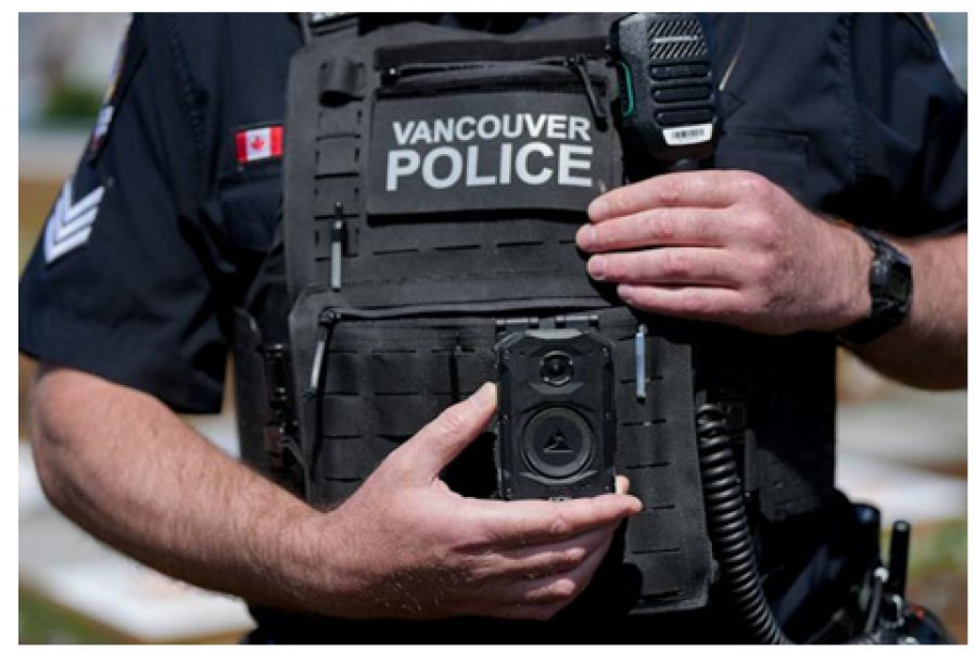 Closeup of a policeman wearing a chest shield with a camera on it.