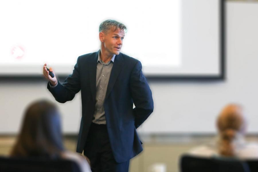 An instructor stands in front of a class presenting.