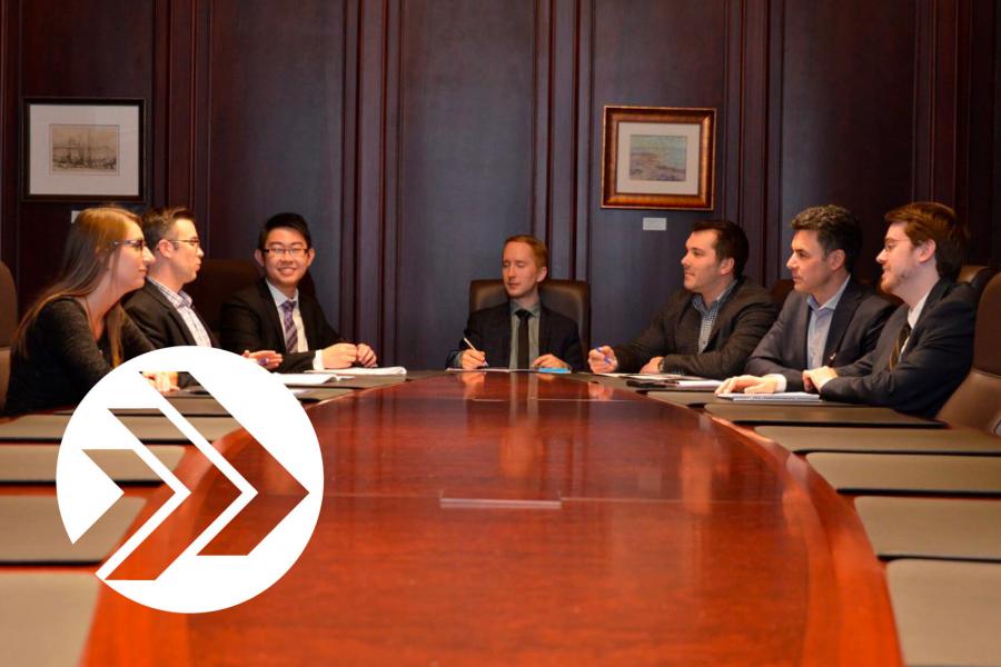 A group of Asper Young Associates sit around a board room table. 