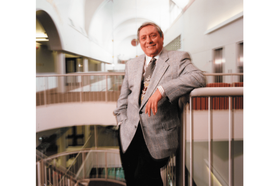 Israel Harold Asper stands at the top of a staircase. 