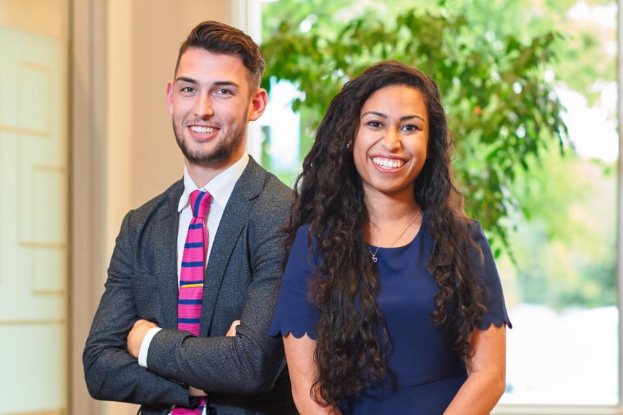 Two Asper School of Business students stand side by side smiling. 