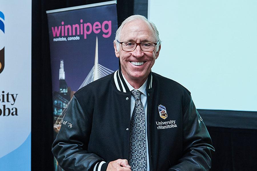 Stu Clark smiling, wearing a UM sports jacket.