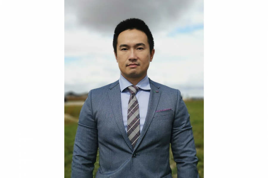 Assistant Hong Li's professional photoshoot. He wears a grey suit with blue shirt