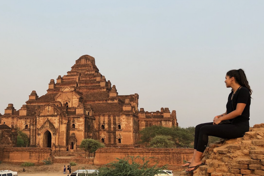 photo of a exchange student looking at a ancient Thai temple during the sunset