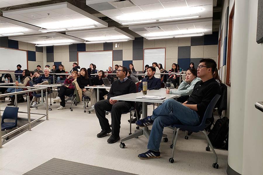 Group of adults sitting in classroom listening to lecture. 