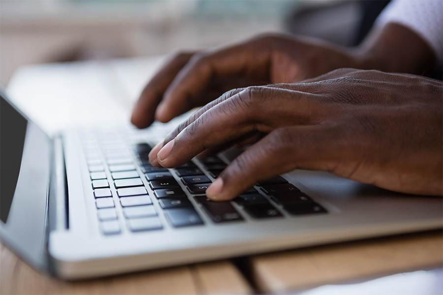 Close up of hands typing on laptop.