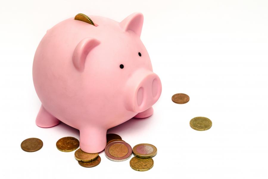 Pink piggy bank on a white background surrounded by coins.