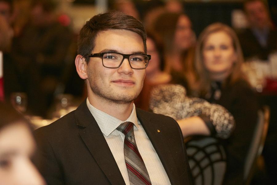 Young man with a suit and tie, wearing glasses.