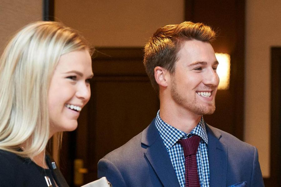 Two young adults, a woman and a man, looking to the side and smiling.