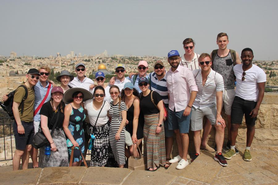 16 adults standing overlooking Jerusalem's Old City.