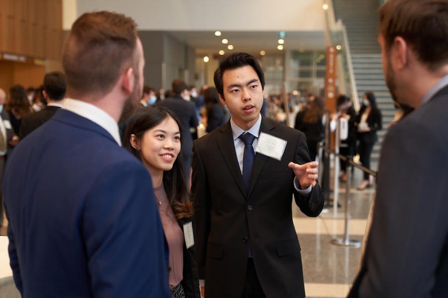 Four Asper students dressed in business clothing talking to each other. 