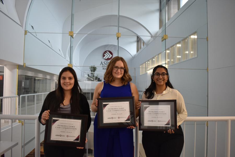 Three students showing off their certificates at an internal competition at Asper