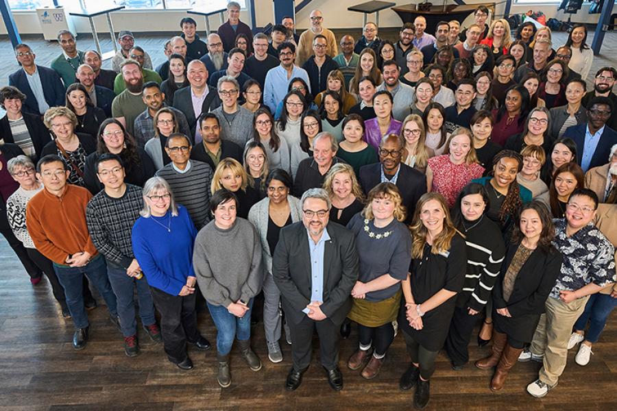 Group of people from the Asper School of Business in business casual clothes looking up at the camera smiling