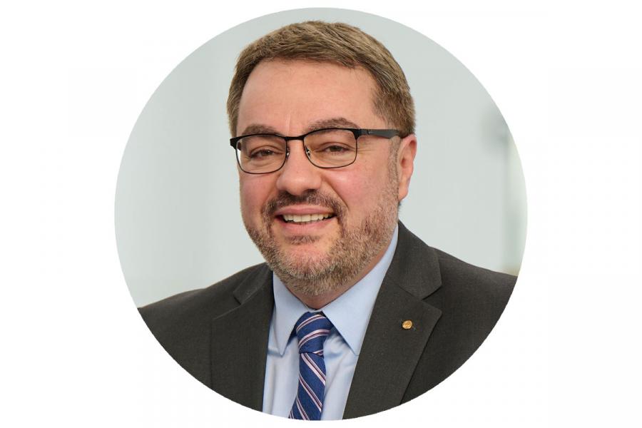 Dean Bruno Silvestre, Asper School of Business, smiling, wearing suit and glasses.