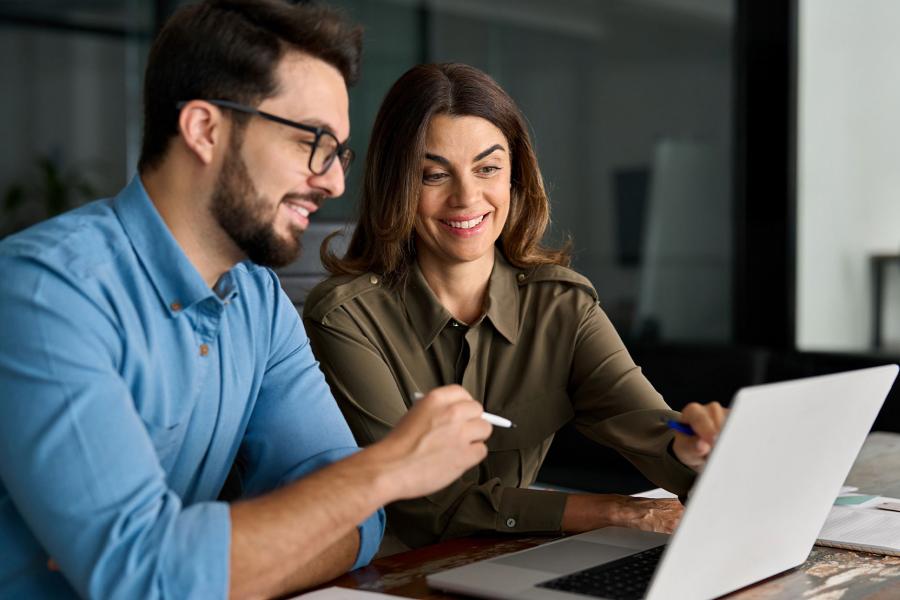 Business leaders discussing AI in front of laptop.