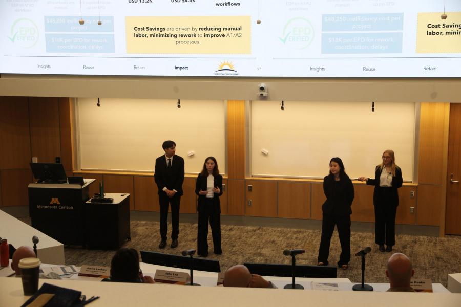 Four students stand at the front of a lecture hall and give a presentation