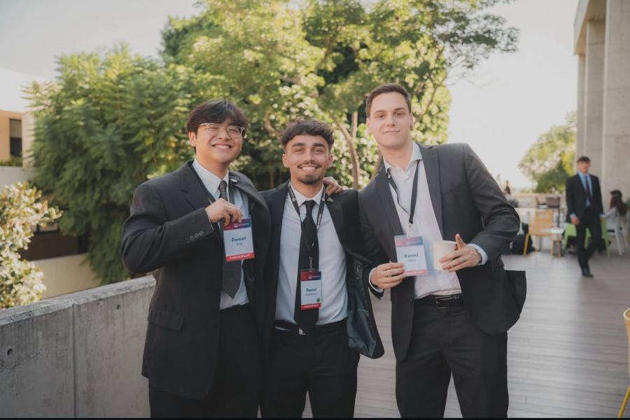 Three people with the same name hold their name tags up in a photo.