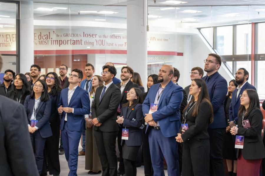 A group of people standing in front of a staircase are all looking above.