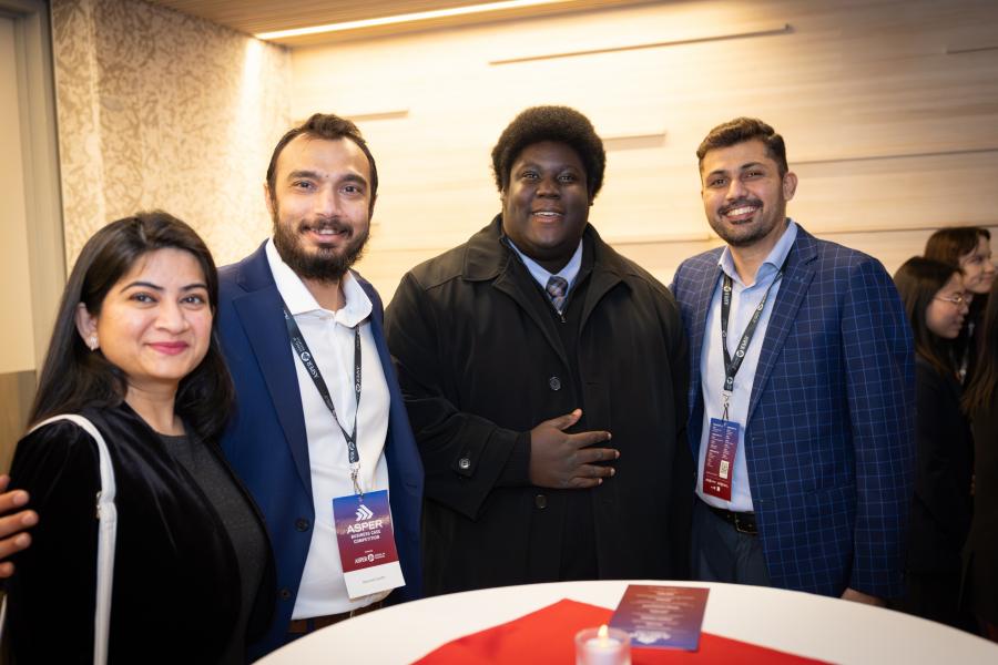 Four people at a dinner pose for a photo at a standing table