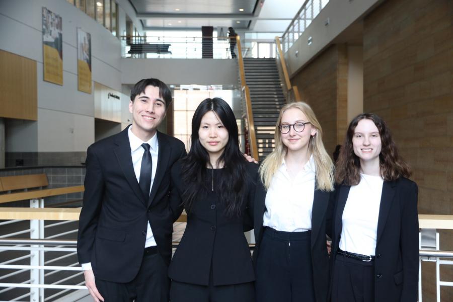 A group of four people pose for a picture in front of a staircase.