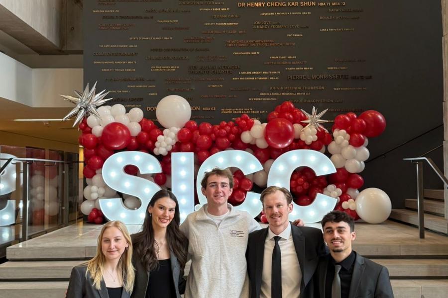 Five people stand in front of a sign that says "SICC"