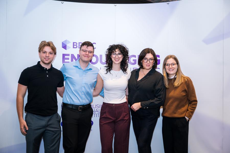 Five people stand together and pose for a photo
